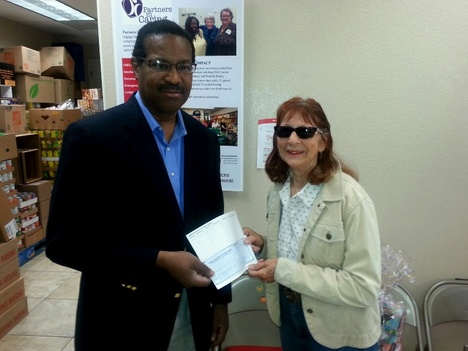 Charity Chair Pat Fulton delivers a donation check to Robert Sanders of Lutheran Social Services of the Southwest